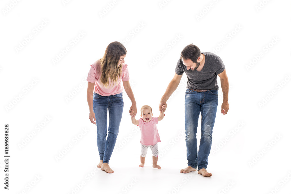 Couple of young parents helping their baby to make first steps on floor in their home Couple of young parents helping their baby to make first steps on floor in their home