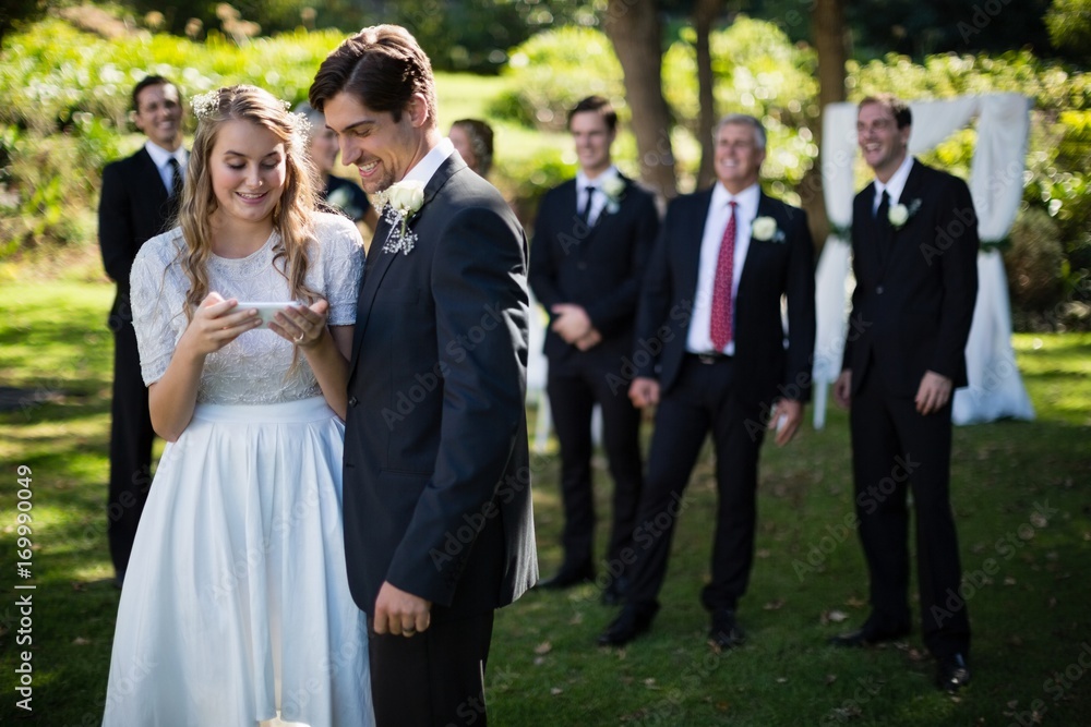 Bride and groom reviewing photographs on mobile phone Bride and groom reviewing photographs on mobile phone