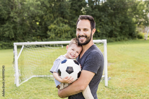 Young father with his little son playing football on football pitch © Louis-Photo