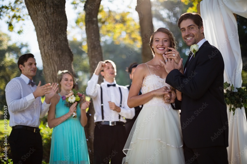 Happy bride and groom showing engagement ring in park