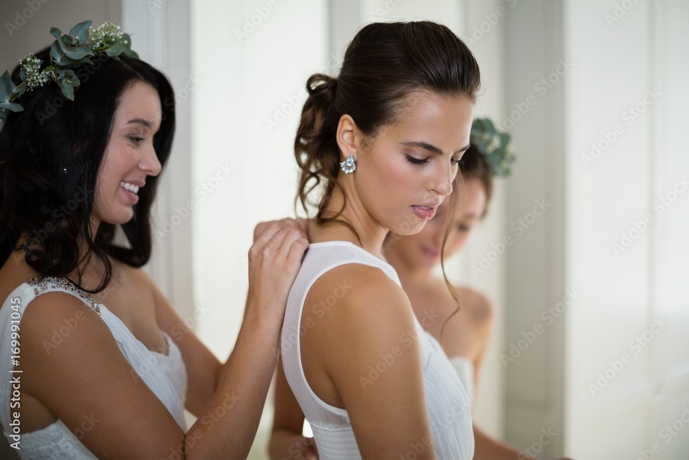 Bridesmaid assisting bride to dress Bridesmaid assisting bride to dress