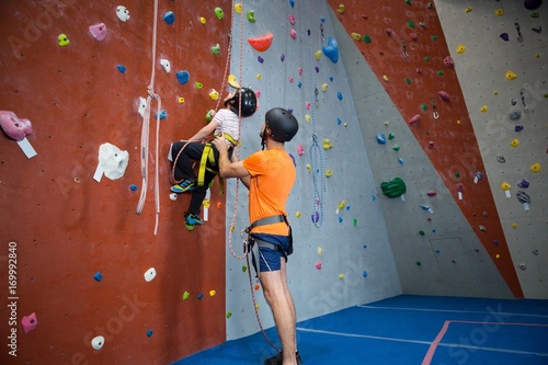 Εκτύπωση καμβά Trainer assisting boy in rock climbing