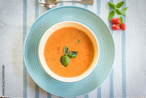 Obraz na plátně Overhead food shot of bowl of warm tomato basil soup