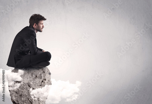 Office worker sitting on top of a rock