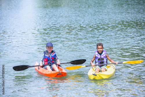  Two diverse boys kayaking together on the lake 