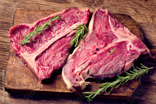 Raw fresh t-bone steak and seasoning on wooden background