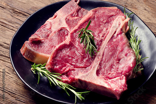 Raw fresh meat t-bone steak and seasoning on wooden background
