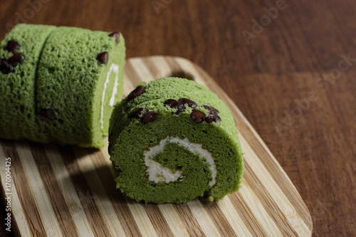 close up matcha green tea roll cake on wood chopping block