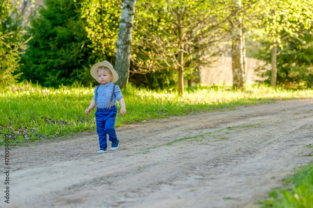 Toddler child outdoors. Rural scene with one year old baby boy with straw hat Toddler child outdoors. Rural scene with one year old baby boy with straw hat