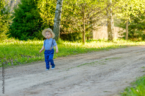 Toddler child outdoors. Rural scene with one year old baby boy with straw hat