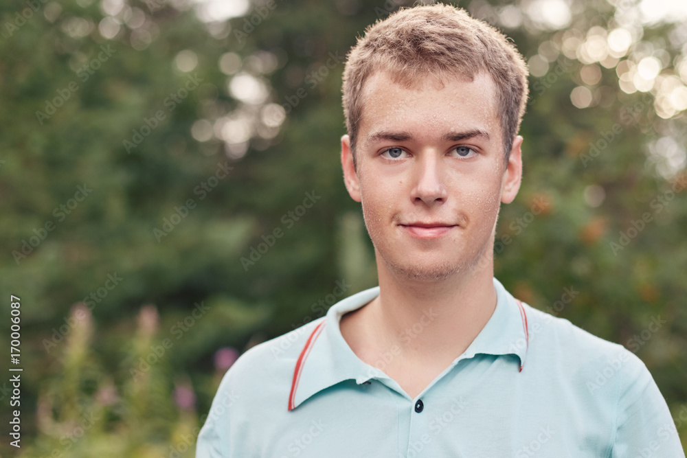 Headshot of teenage European tennis player with blue eyes, athletic body in forest in morning sun is wet after training activity with drops of sweat on his young face. Healthy lifestyle concept. Headshot of teenage European tennis player with blue eyes, athletic body in forest in morning sun is wet after training activity with drops of sweat on his young face. Healthy lifestyle concept.