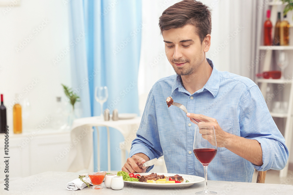 Young man eating delicious ribs in restaurant Young man eating delicious ribs in restaurant