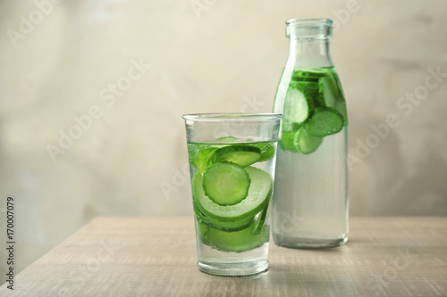 Delicious refreshing water with mint and cucumber in glassware on wooden table
