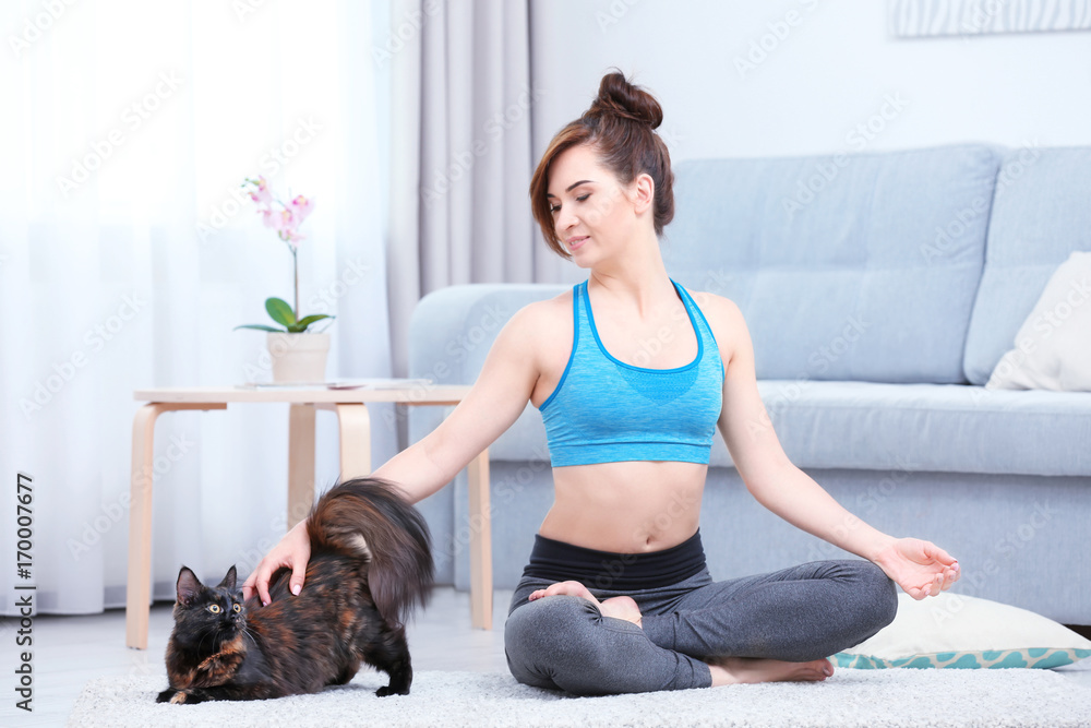 Young beautiful woman with cat practicing yoga pose at home Young beautiful woman with cat practicing yoga pose at home