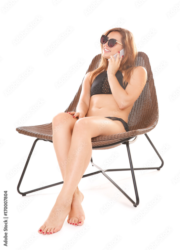 Beautiful young woman talking on mobile phone while sitting in wicker chair Beautiful young woman talking on mobile phone while sitting in wicker chair