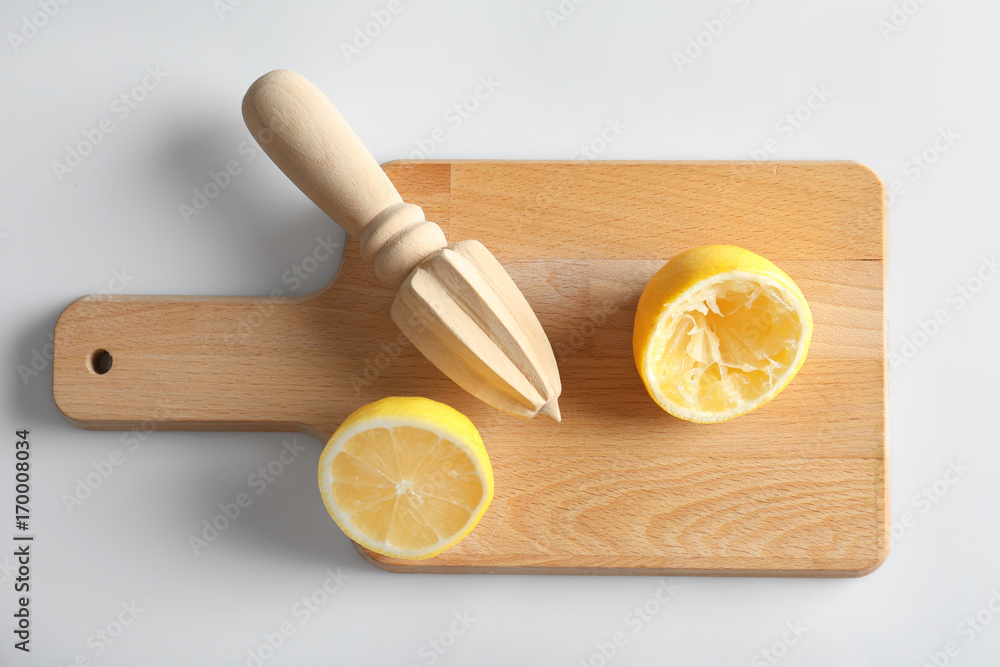 Cutting board with cut lemon and wooden citrus reamer on white background Cutting board with cut lemon and wooden citrus reamer on white background