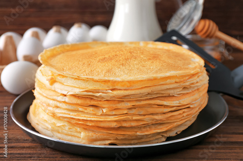 Stack of delicious thin pancakes on frying pan, closeup