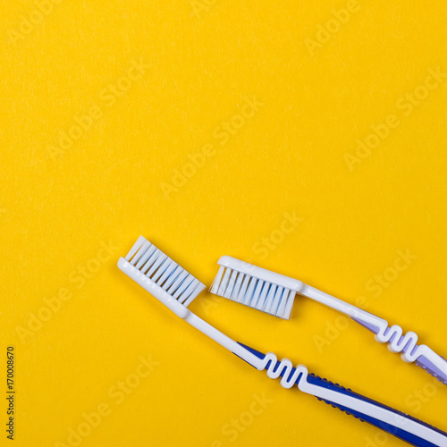 two Toothbrushes on yellow background