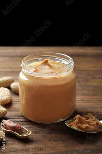 Jar with creamy peanut butter on table