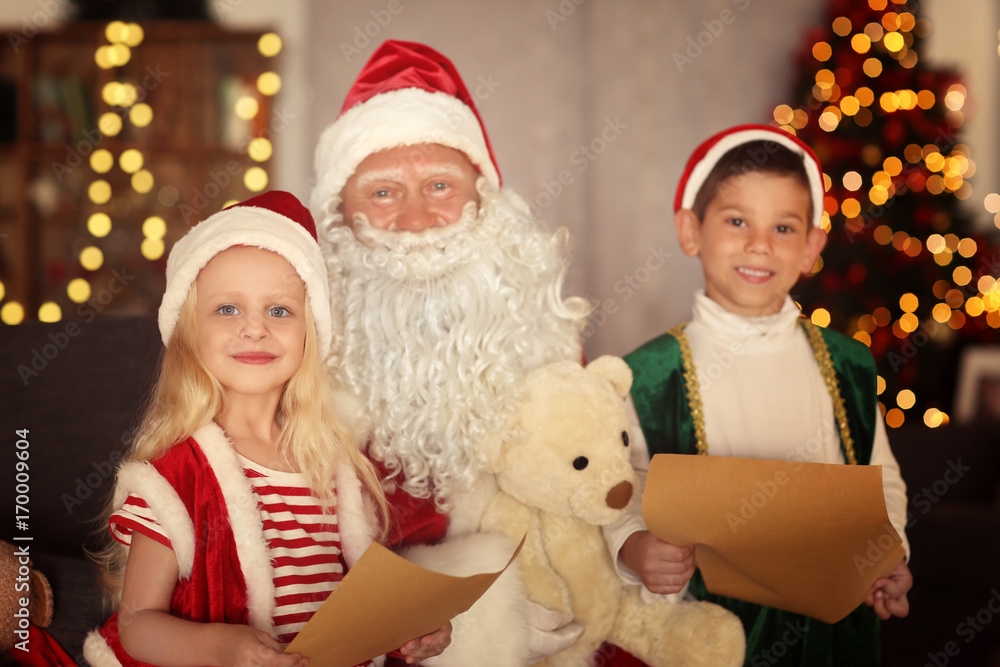 Cute elf kids with letters and Santa Claus in room with beautiful Christmas decoration Cute elf kids with letters and Santa Claus in room with beautiful Christmas decoration