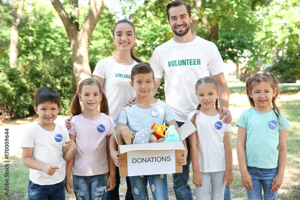 Young volunteers and children with box of donations outdoors Young volunteers and children with box of donations outdoors