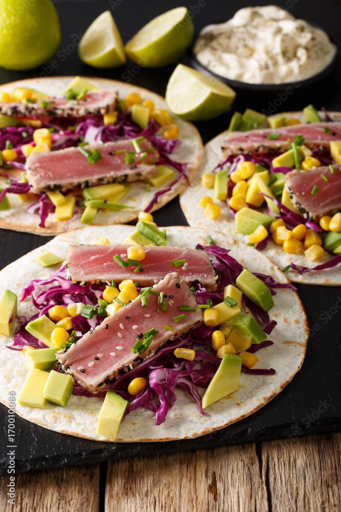 tortilla with tuna steak, sesame and fresh vegetables close-up. vertical tortilla with tuna steak, sesame and fresh vegetables close-up. vertical
