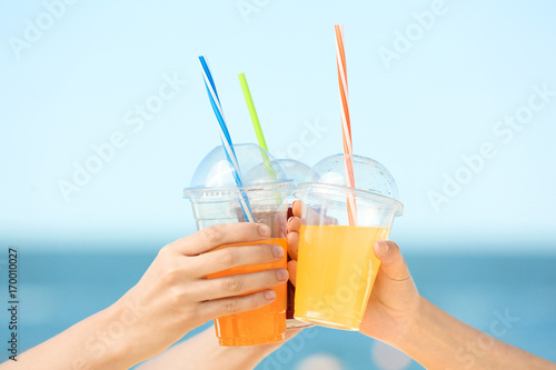 Hands of beautiful young women with drinks at sea resort