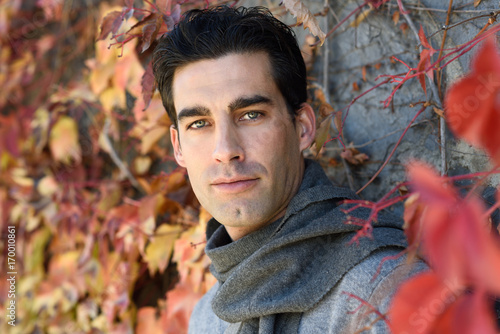 Handsome man wearing winter clothes in autumn leaves background