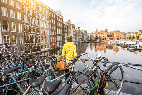 Photography Young woman in yellow raincoat enjoying morning view on the beautiful cityscape