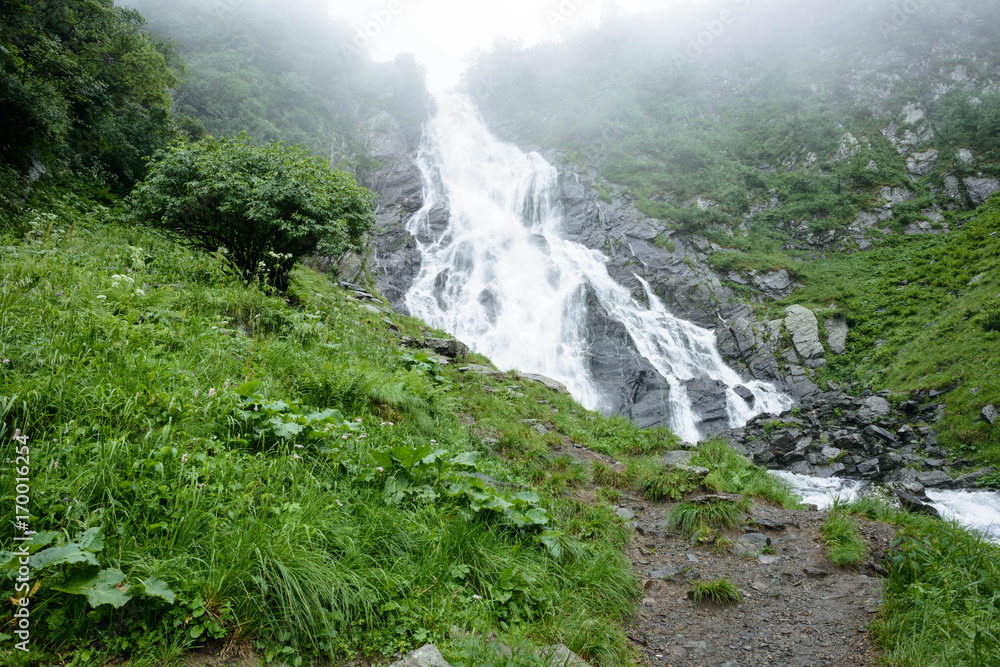 Travel to the waterfall  Balea in Fagarash mountains. Rocky waterfall in the mountains. The place of Carpathians Romania, near the Transfagarasan road.
