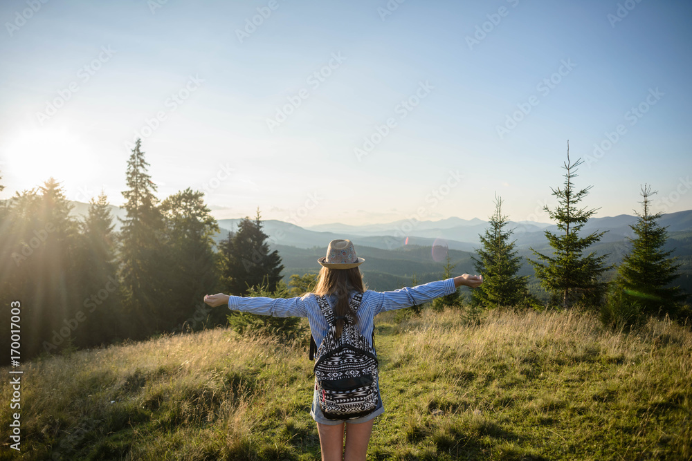 Φωτογραφία Young girl wearing a hat with a backpack, enjoying the sunset on the top of the mountains in the Carpathians