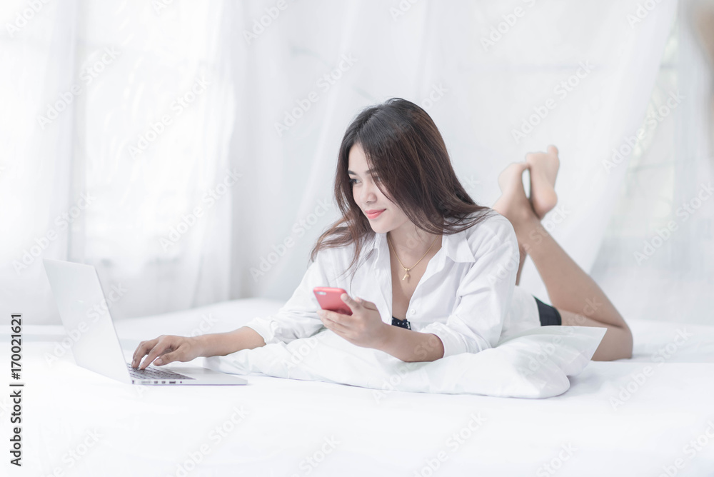 Young woman writing on a computer while in bed Young woman writing on a computer while in bed
