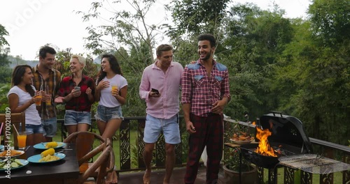 Young People Talking Using Cell Smart Phones While Latin Man Cooking Barbecue Friends Group Gathering On Summer Terrace Communication Slow Motion 60