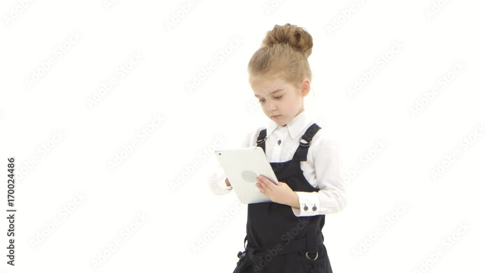 School girl first grader communicates by tablet on white background School girl first grader communicates by tablet on white background