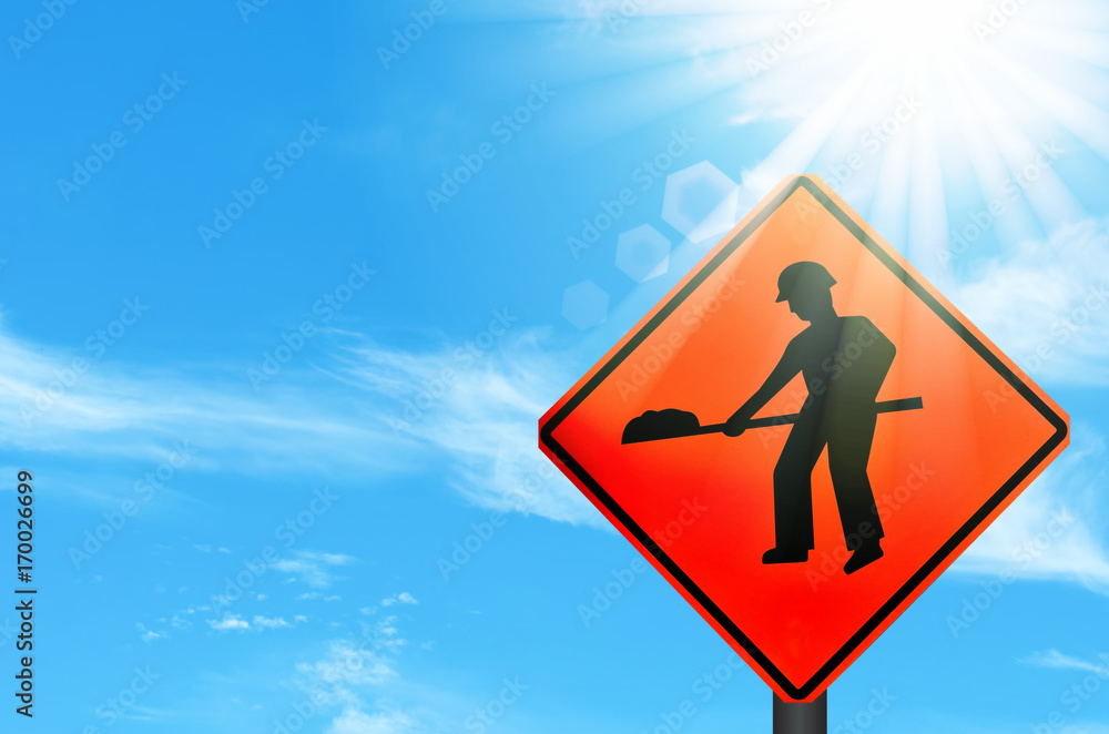 Construction warning sign on blue sky and sun light white clouds background.
