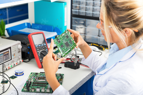 Obraz na płótnie Female electronic engineer checking circuit board in laboratory