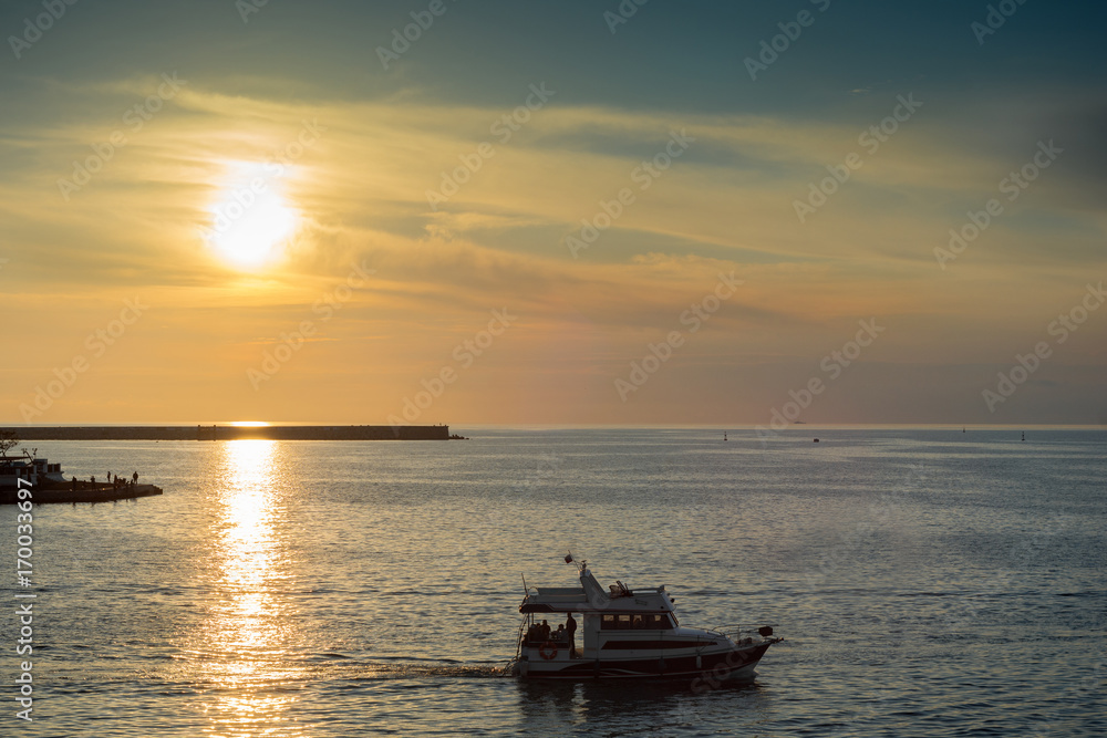 beautiful sunset on the coast. the boat runs along the seashore
