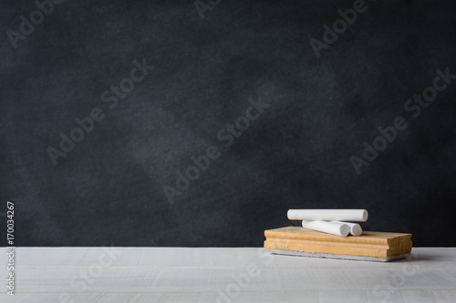 Chalk and eraser board on the white desk. Blackboard background