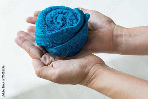 Single blue towel rolled design in rose flower shape on hand. Prepare for guest in luxury hotel that welcome from travel. Cloth for wiping hands in restaurant.