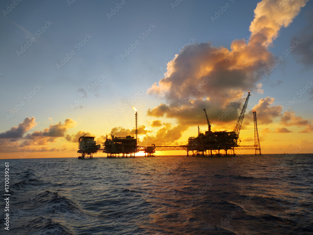 Offshore oil and gas platform in the middle of the ocean with beautiful sunset.