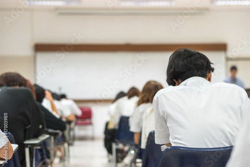 Education blur background back view university students writing answer doing exam in school classroom photo