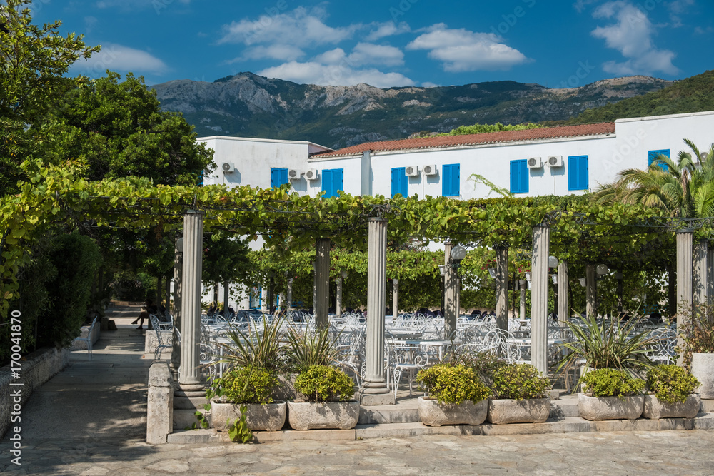 Restaurant garden on the Mediterranean square with white furniture in the vine shade