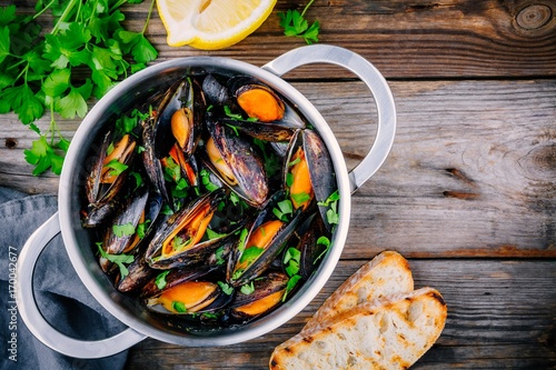Delicious seafood mussels with with sauce and parsley.  Lemon and baguette . ...