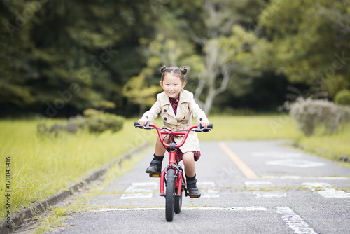 Little girl riding a red bicycle