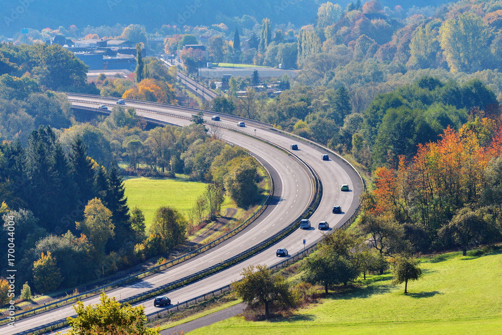 Die Autos fahren auf der Autobahn an einem sonnigen Tag im Herbst