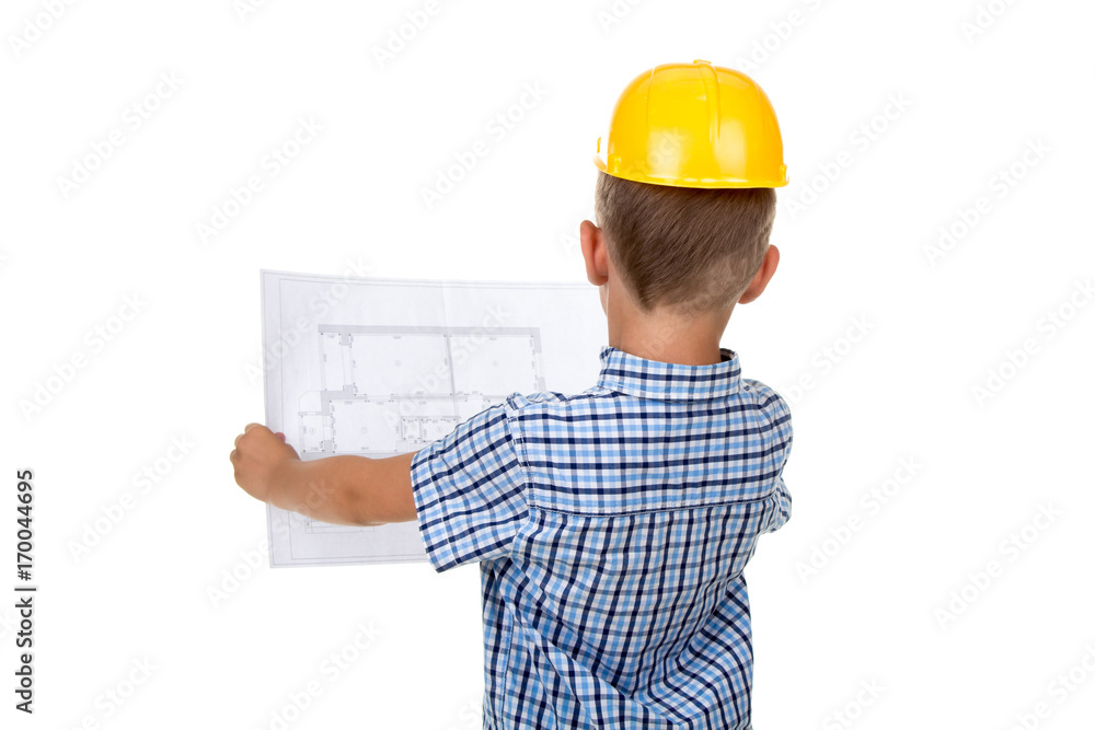 Cute serious builder boy is reading a building paper plan, turned back, isolated on white Cute serious builder boy is reading a building paper plan, turned back, isolated on white