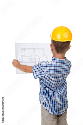 Young serious builder reading a construction plan, turned back, isolated on white