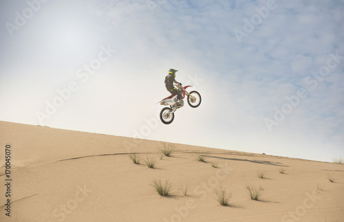 Obraz na płótnie A dirt bike rider does an aerial jump in the desert sand dunes w salonie