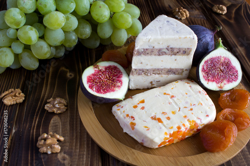 Cheese plate with fruit on the wooden background