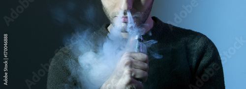 Isolated young man on a dark background holding an electronic ci